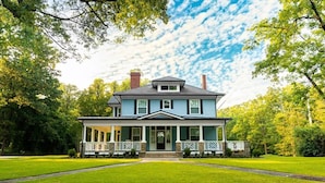 A two-story house with a porch, surrounded by a well-maintained lawn and trees. - Historic Gem in the Heart of Norcross (Norcross)