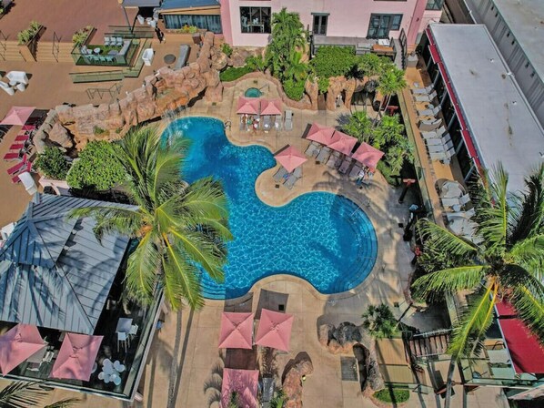 A resort with a large, irregularly shaped pool surrounded by palm trees and lounge chairs. - High Floor -Miami Beach Pool, Beach Service-1219 (Miami Beach)