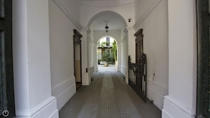 A corridor with white walls, a tiled floor, and an arched ceiling.