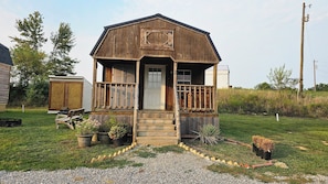 A wooden cabin with a porch, a door, and a small garden area with potted plants. - Cozy cabin 8 minutes from Ark Encounter!! (Dry Ridge)