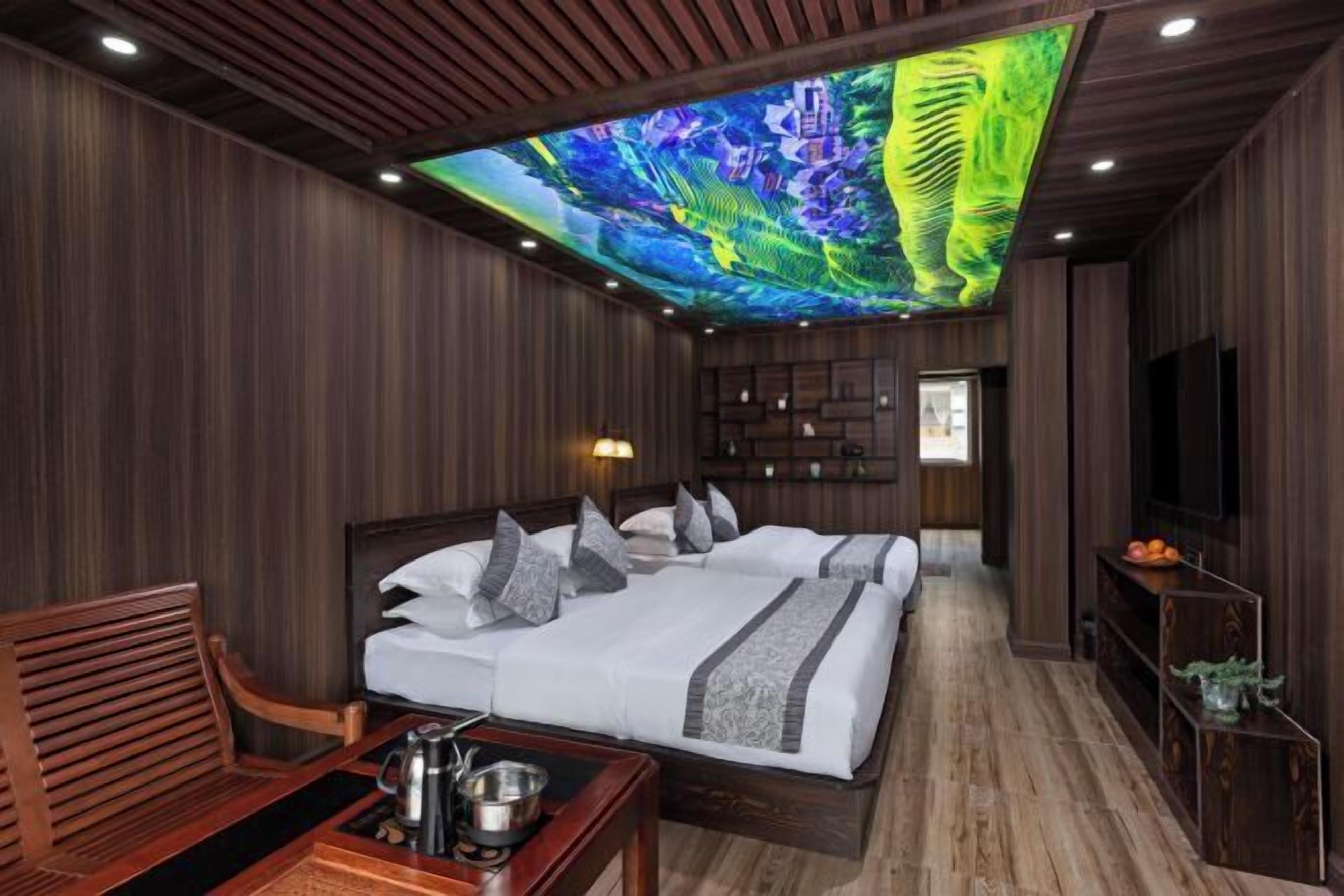 A hotel room with a large bed, a desk with a kettle, and a television.