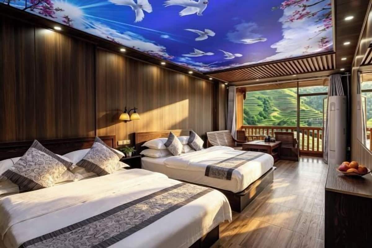 Ein Schlafzimmer mit zwei Betten, Holzboden und Blick ins Grüne.