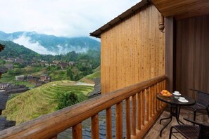 A wooden balcony with a view of terraced fields and mountains.