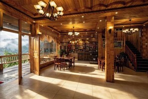 A wooden interior with a dining area, bar, and staircase. - Yu Yong Guesthouse (Longsheng Longji Rice Terraces) (Longsheng)