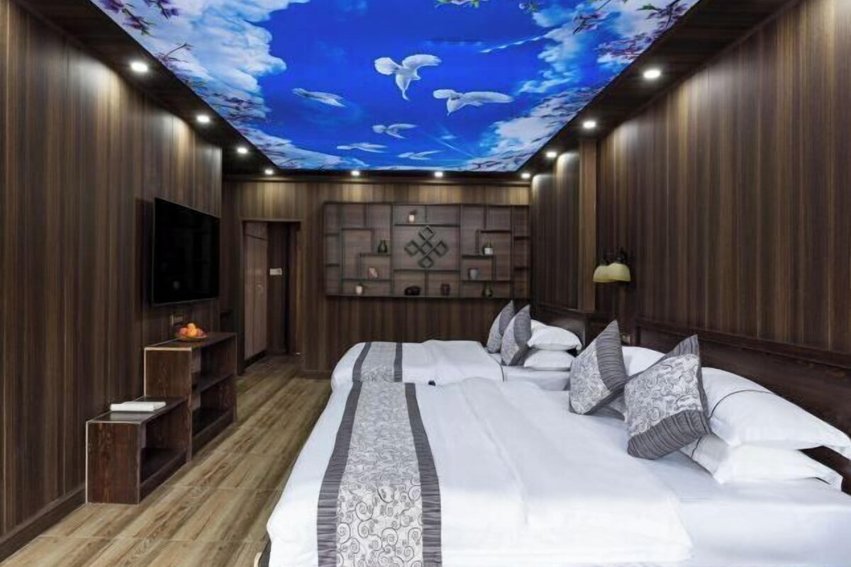 A bedroom with a large bed, a TV, a ceiling mural, and wooden paneling.