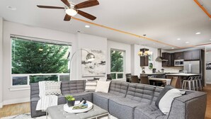 Ein modernes Wohnzimmer mit grauem Ecksofa, einem Couchtisch und einem Deckenventilator.
