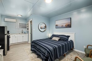 Een slaapkamer met een bed, nachtkastje, spiegel en een schilderij aan de muur.