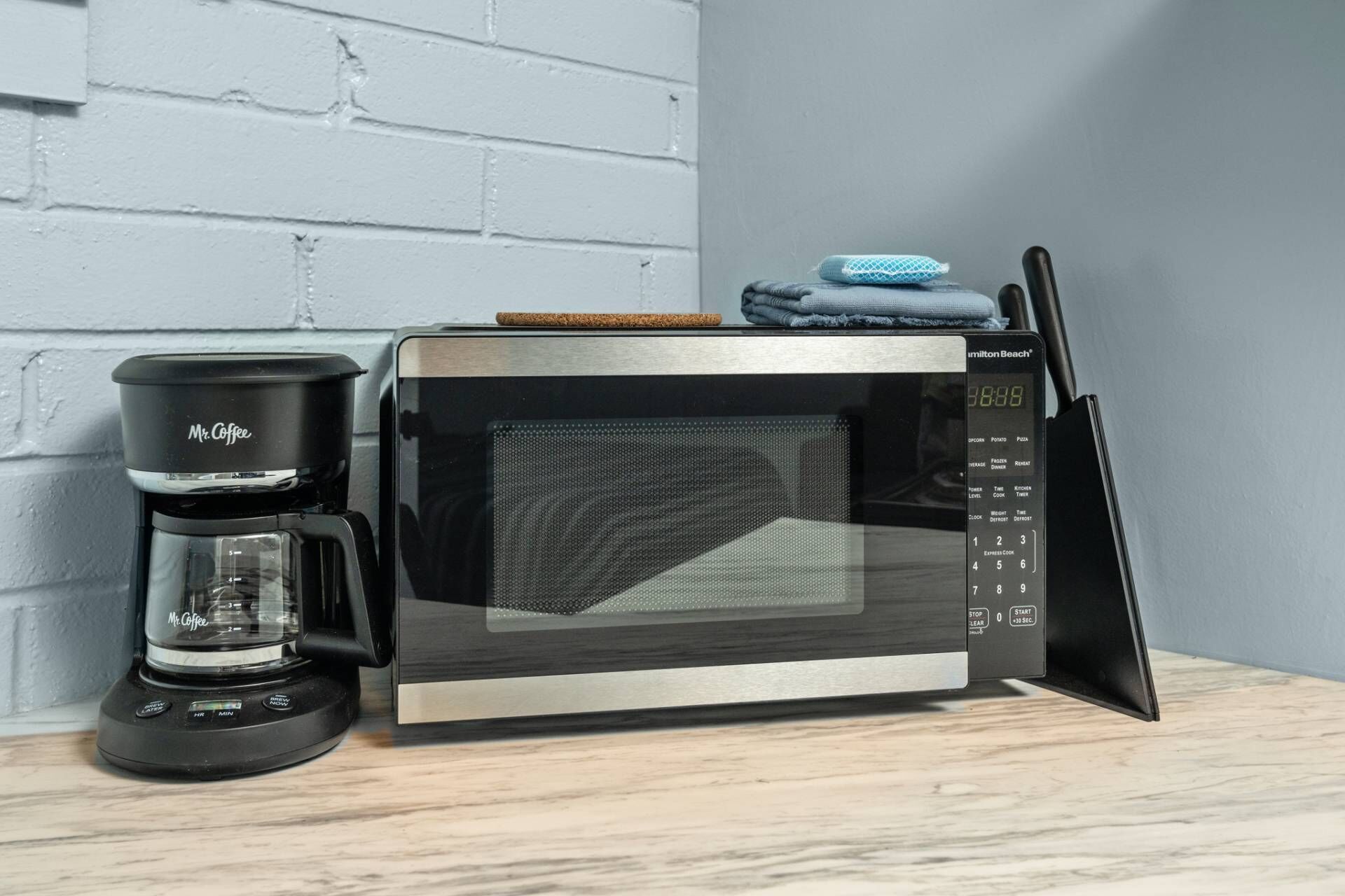 A kitchen with a microwave, a coffee maker, and a knife block.