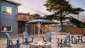 A patio area with Adirondack chairs, a fire pit, and a wooden pergola.