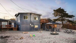 A two-story house with a covered patio and a fire pit in the backyard.