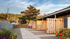 A covered outdoor area with a paved walkway, wooden fences, and potted plants. - Incredible Central Rockaway Location, *Pet Friendly*, Patio, Walk to Beach and Downtown, Unit 2 (Rockaway Beach)