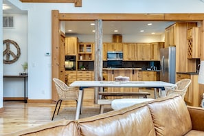 A modern kitchen with wooden cabinets, a stainless steel refrigerator, and a dining area with a table and chairs.