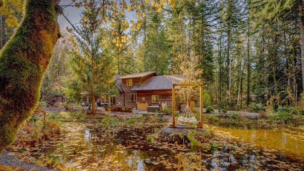 A cabin with a wooden exterior, surrounded by a pond with floating leaves, and a boat docked nearby. - Spectacular Private Mountain Cabin on 6 Acres, Epic Outdoor, Hot Tub, Game Room, Pond (Rhododendron)