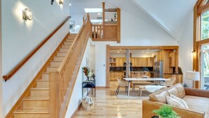 A spacious living area with a wooden staircase, a dining area, and a kitchen with wooden cabinets. - Spectacular Private Mountain Cabin on 6 Acres, Epic Outdoor, Hot Tub, Game Room, Pond (Rhododendron)