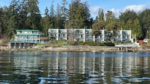 A waterfront hotel with multiple buildings, a dock, and a rocky shoreline. - INN OF THE SEA - Stunning views~ Oceanfront Pool & Hot Tub, Private Dock (Ladysmith)