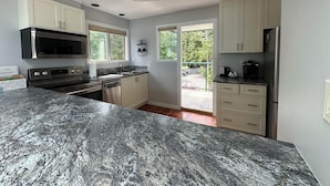A modern kitchen with granite countertops, stainless steel appliances, and a view of the outdoors. - INN OF THE SEA - Stunning views~ Oceanfront Pool & Hot Tub, Private Dock (Ladysmith)