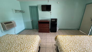 Een kamer met twee bedden, een televisie, een dressoir, een magnetron en een airconditioner.