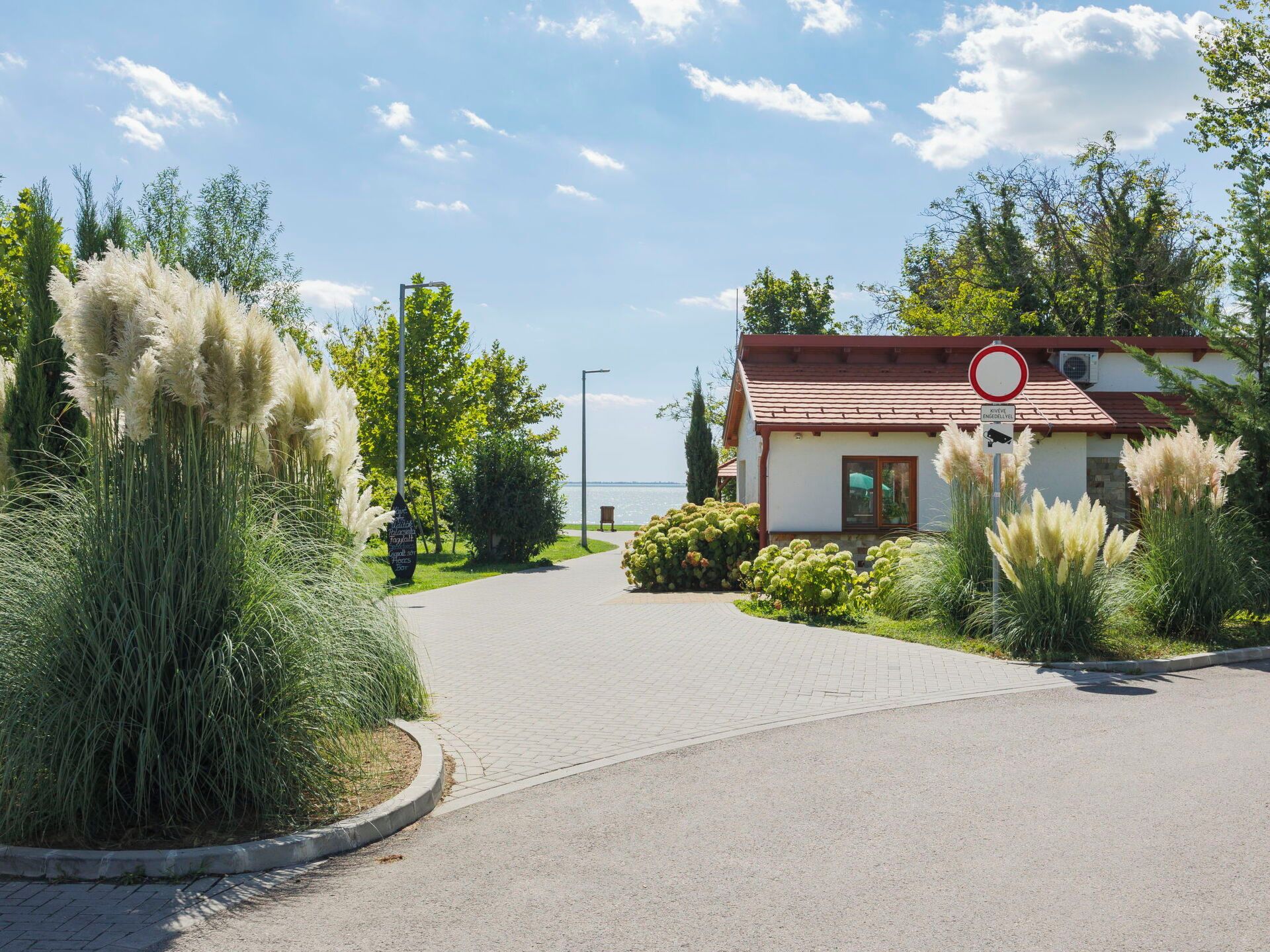 A paved driveway leading to a building with a red roof and a circular no-entry sign.
