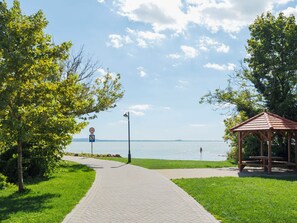 A paved walkway leading to a body of water with a gazebo and picnic tables. - Stunning  villa for 4 guests with A/C, WIFI, TV, terrace and pets allowed (Balatonfüred)