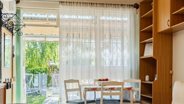 Una habitación acogedora con una mesa de comedor, dos sillas, un sofá, un televisor y una estantería.