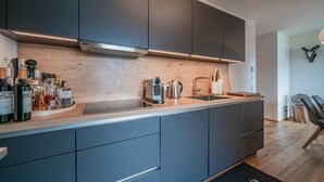 Una cocina moderna con armarios oscuros, encimera de madera y estufa integrada.