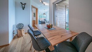 Un comedor moderno con una mesa y sillas de madera, un cuenco de fruta y una lámpara colgante.