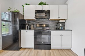 A kitchen with stainless steel appliances, white cabinets, and a honeycomb backsplash.