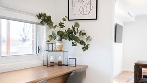 A modern dining area with a wooden table, chairs, a potted plant, and a framed artwork on the wall. - Getaway on Curran. EV + Firepit. Walk to CBD. (Orange)