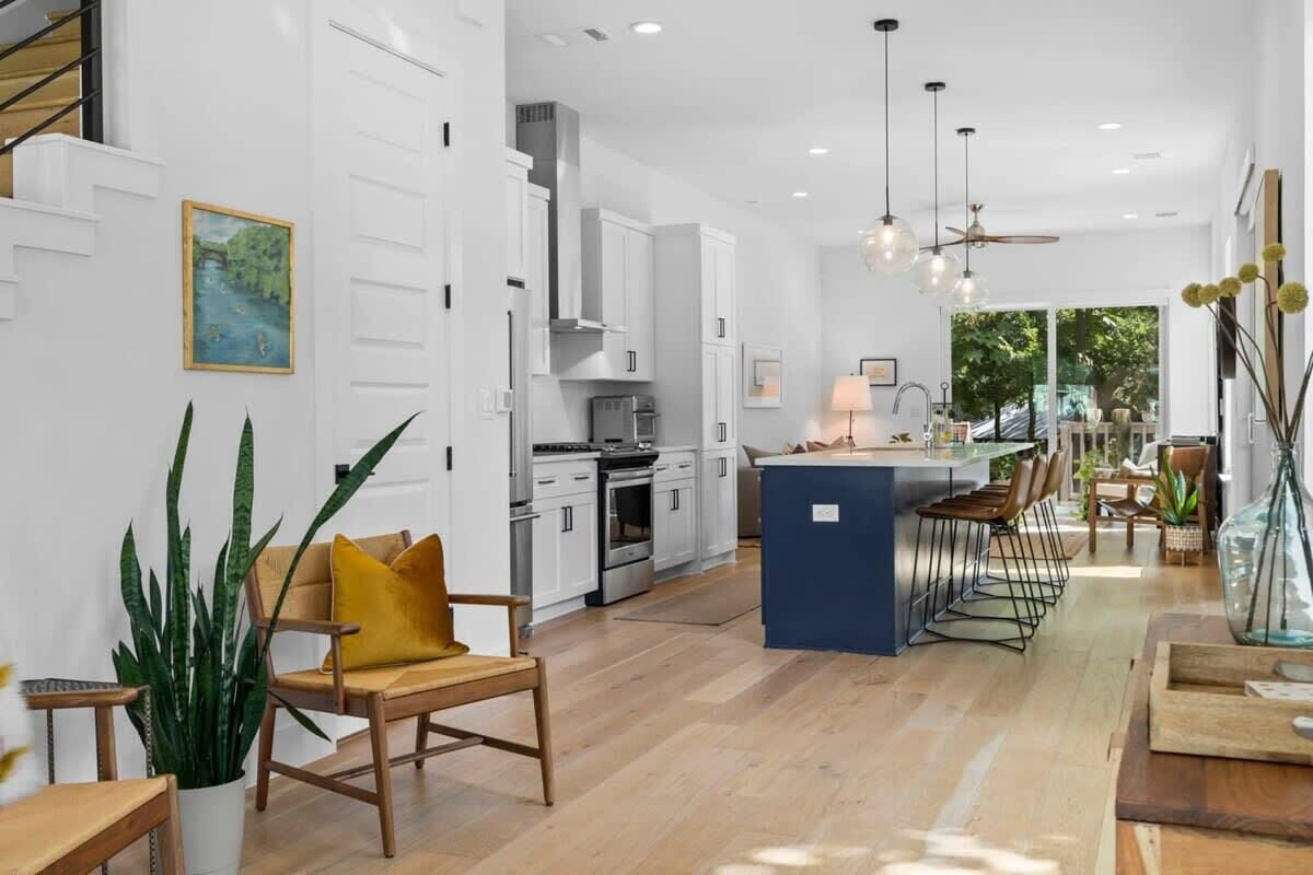 A modern kitchen with white cabinets, a central island, and pendant lighting.