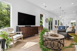 A modern living room with a flat-screen TV, wooden furniture, and a large window.