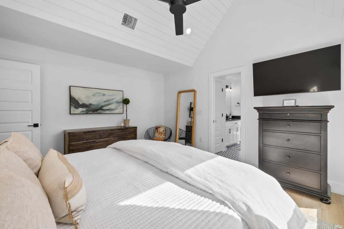 Quarto com cama, penteadeira, espelho e televisão de tela plana.
