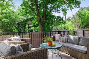 An outdoor seating area with wicker furniture and a round glass table.
