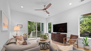 A modern living room with a sofa, armchairs, a coffee table, and a television. - Cherrywood Home Near UT / ATX / Private Backyard (Austin)