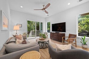Ein modernes Wohnzimmer mit einer Couch, Sesseln, einem Couchtisch und einem Fernseher.