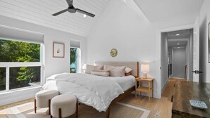 A bedroom with a bed, bedside tables, a ceiling fan, and a view of greenery outside. - Cherrywood Home Near UT / ATX / Private Backyard (Austin)
