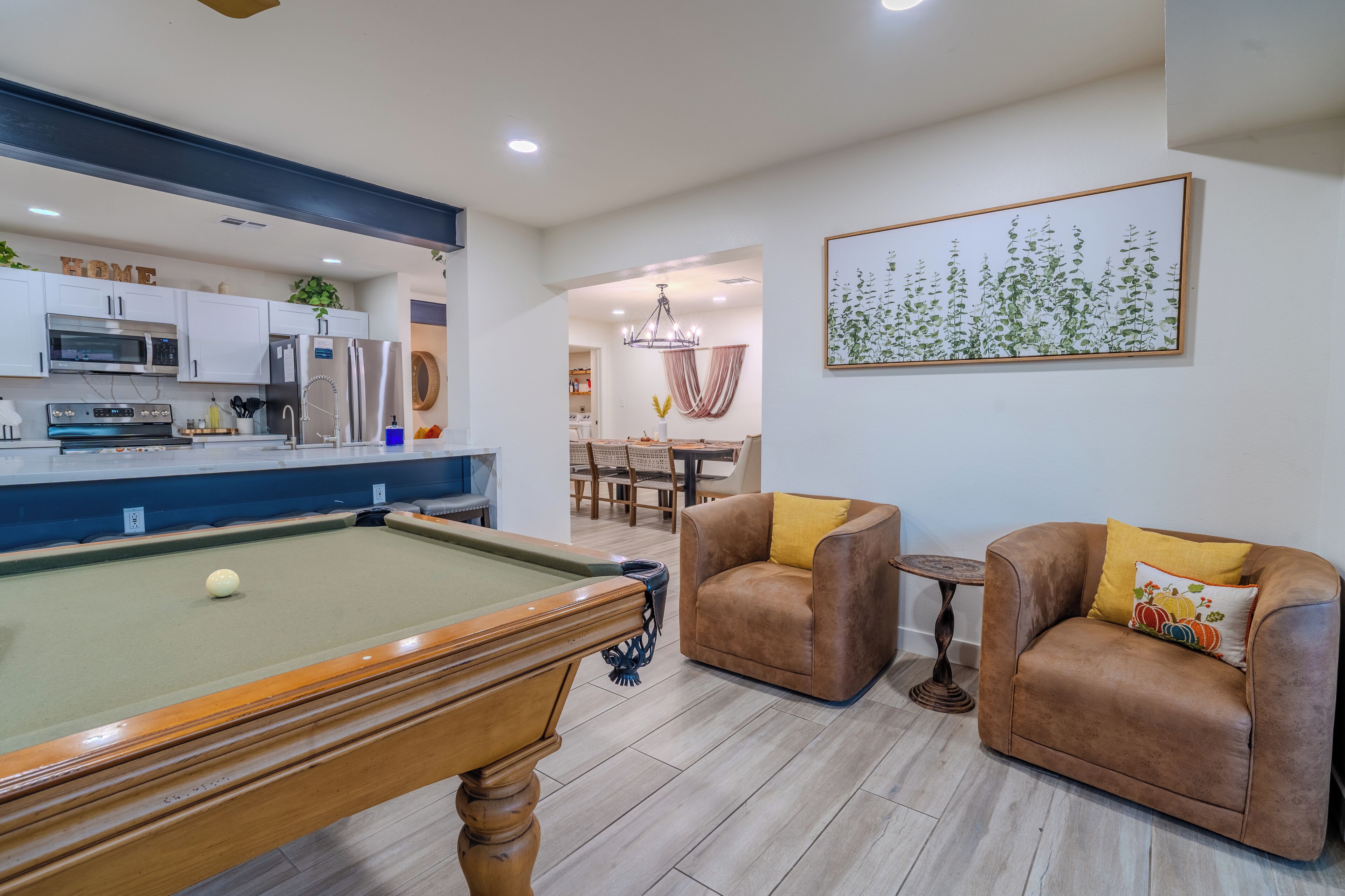 A modern living room with a pool table, leather sofas, and a dining area.