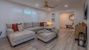 A modern living room with a sectional sofa, a ceiling fan, recessed lighting, a wooden cabinet, and a bench. - Luxurious Cascada Oasis ~ Cozy ~ Games ~ King Beds (Litchfield Park)