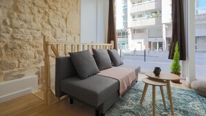 Een moderne woonkamer met een bank, een klein rond tafeltje en een plant in pot.