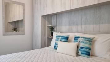 Una camera da letto con un letto grande, una testiera in legno, un piccolo ripiano con una pianta e uno specchio a parete.