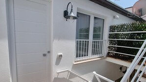 A white exterior with a sliding door, a small window with a white frame, a white railing, and a wooden deck with a patterned mat. - Piccolo Nida 18 in Cattolica (Cattolica)