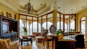 A spacious living area with a large window, a fireplace, and a dining area with a view. - Villa Castello- Water Views Resort Amenities (Placencia)