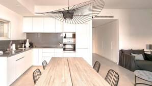 A modern kitchen with white cabinets, a wooden dining table, and black chairs. - Hovevei Tsiyon Magnolia (Tel Aviv)