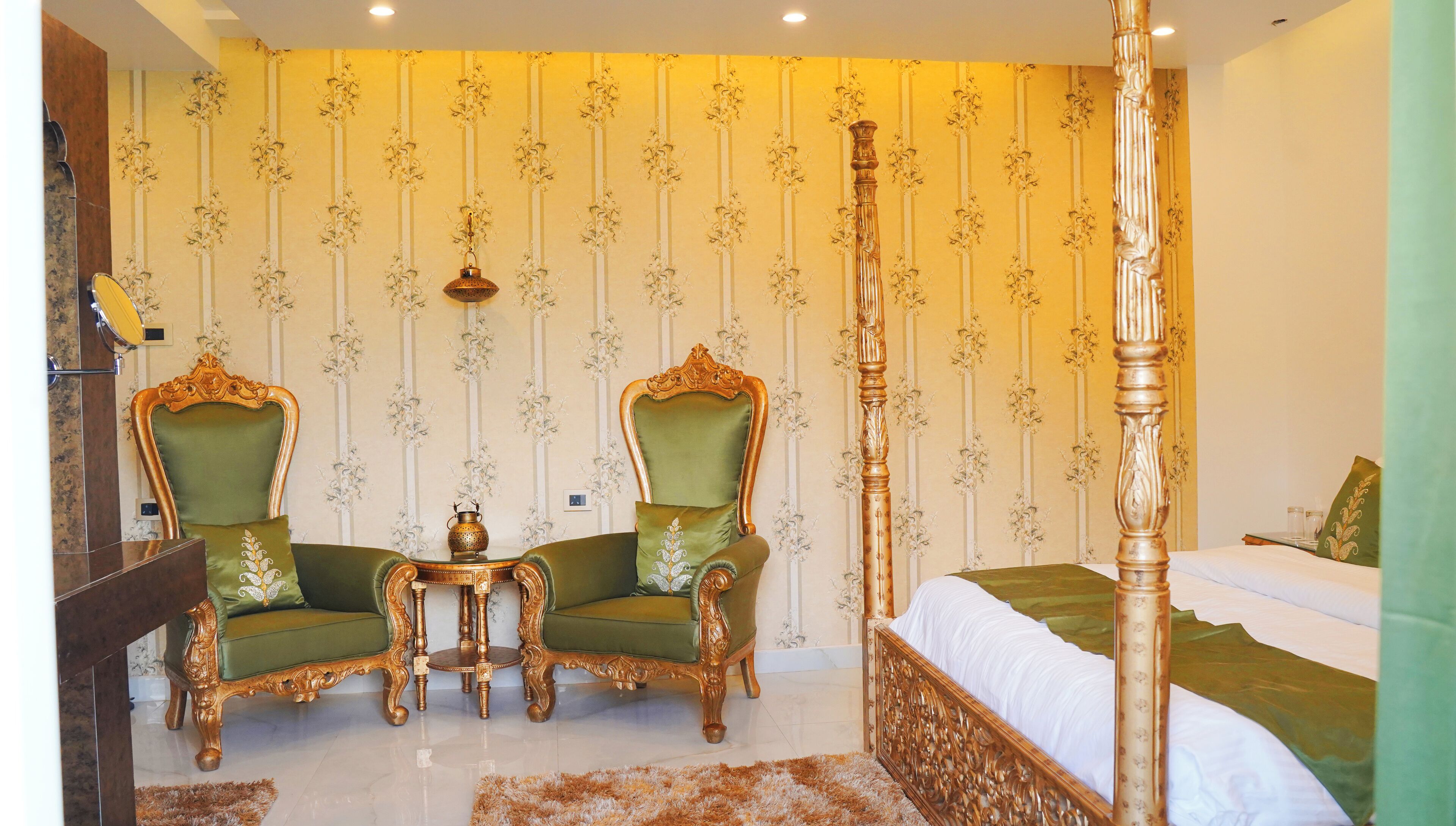 A room with a four-poster bed, two green upholstered chairs, a small table, and a decorative wall with vertical stripes.