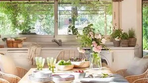 A dining area with wicker furniture, a wooden table, and a view of greenery outside. - Luxury villa on a private estate in Toledo w/pool and views of Sierra de Gredos. (mejorada)