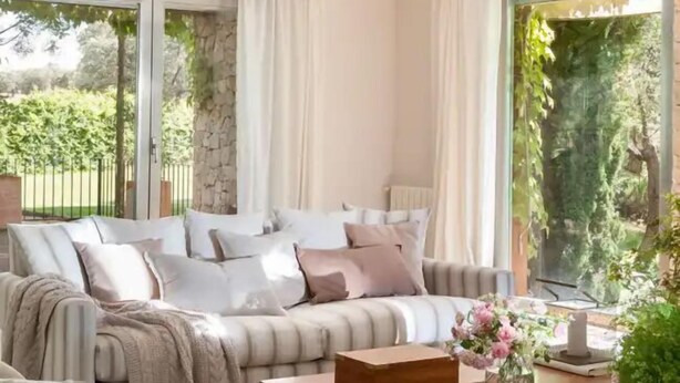 A cozy living room with a large sofa, a wooden coffee table, and a view of greenery outside. - Luxury villa on a private estate in Toledo w/pool and views of Sierra de Gredos. (mejorada)