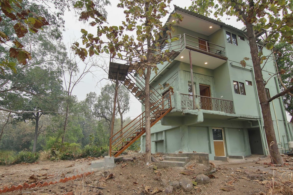 A two-story building with a staircase leading to the upper floor, surrounded by trees and vegetation.