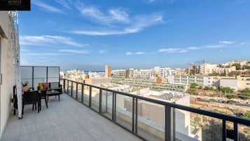 A balcony with a view of a cityscape, a seating area with a table and chairs, and a sign reading "360 ESTATES".