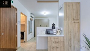 A modern kitchen with a microwave, kettle, and wooden cabinets.