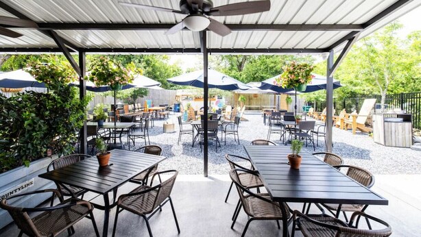 An outdoor patio area with tables and chairs, umbrellas, and potted plants. - Comfort Suite | Near Mercer University & Downtown (Macon)
