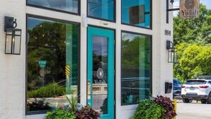 A building with large windows, a teal door, and potted plants in front. - Comfort Suite | Near Mercer University & Downtown (Macon)